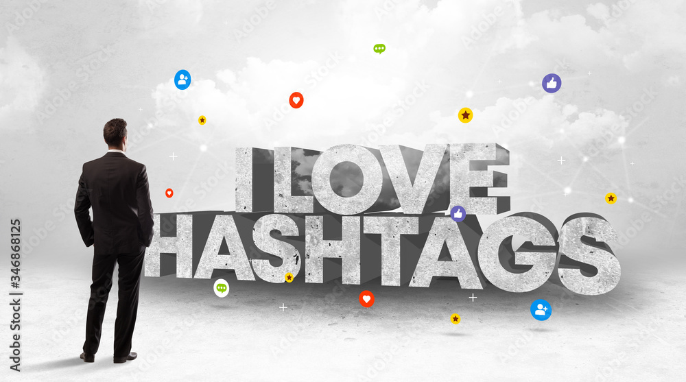 Young businessman standing in front of I LOVE HASHTAGS inscription, social media concept Young businessman standing in front of I LOVE HASHTAGS inscription, social media concept