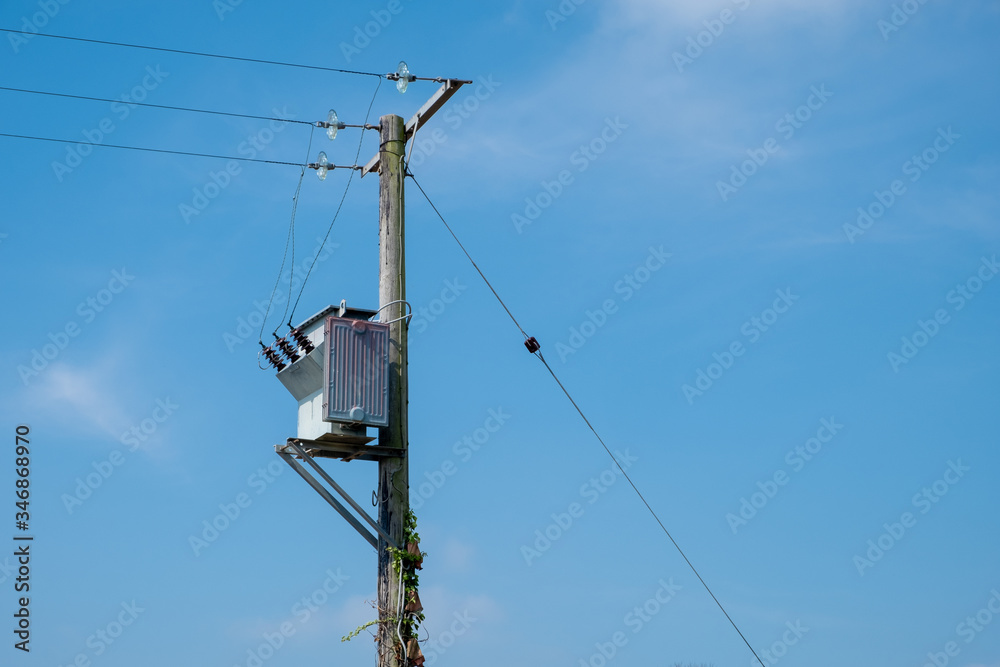 A small pole-mounted electrity transformer against a blue sky in England, UK A small pole-mounted electrity transformer against a blue sky in England, UK