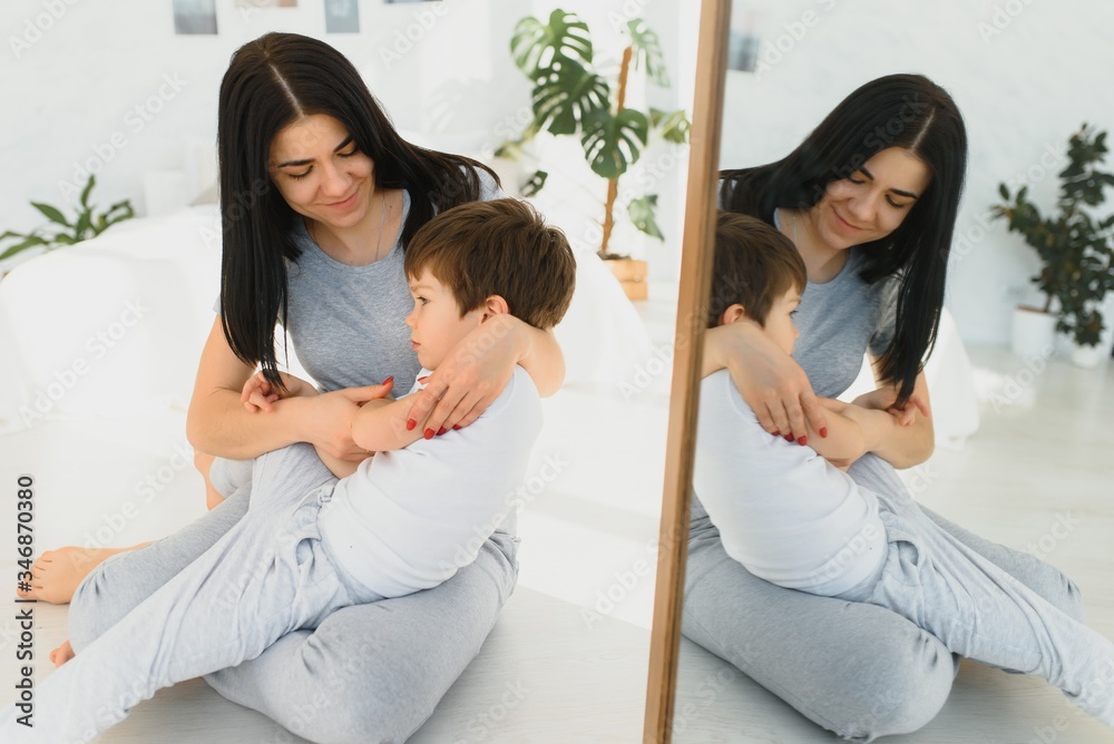 Cheerful mother sitting on couch in cozy light living room holds on lap tickles of little son enjoy funny activities on weekend at home, have fun together, priceless time with preschool child concept Cheerful mother sitting on couch in cozy light living room holds on lap tickles of little son enjoy funny activities on weekend at home, have fun together, priceless time with preschool child concept