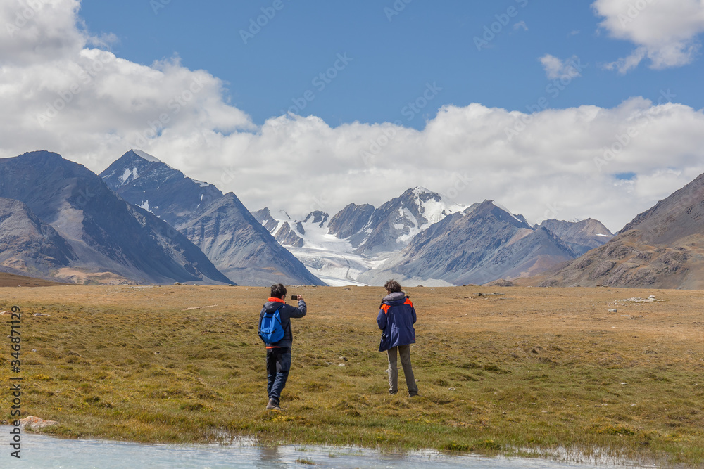 Tourists relax near the lake and enjoys beautiful views of the mountains of the Mongolian Altai