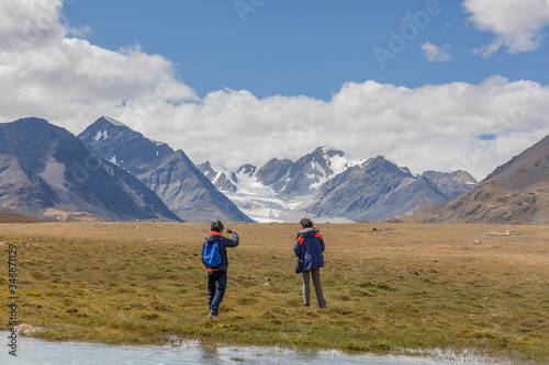 Tourists relax near the lake and enjoys beautiful views of the mountains of the Mongolian Altai