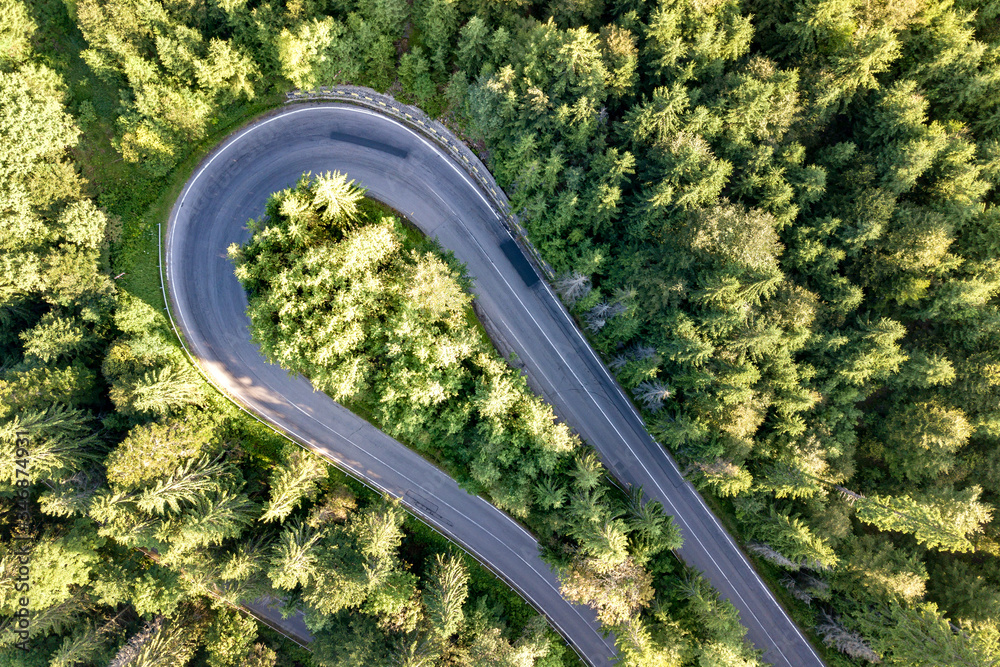 Aerial view of winding road in high mountain pass trough dense green pine woods. Aerial view of winding road in high mountain pass trough dense green pine woods.