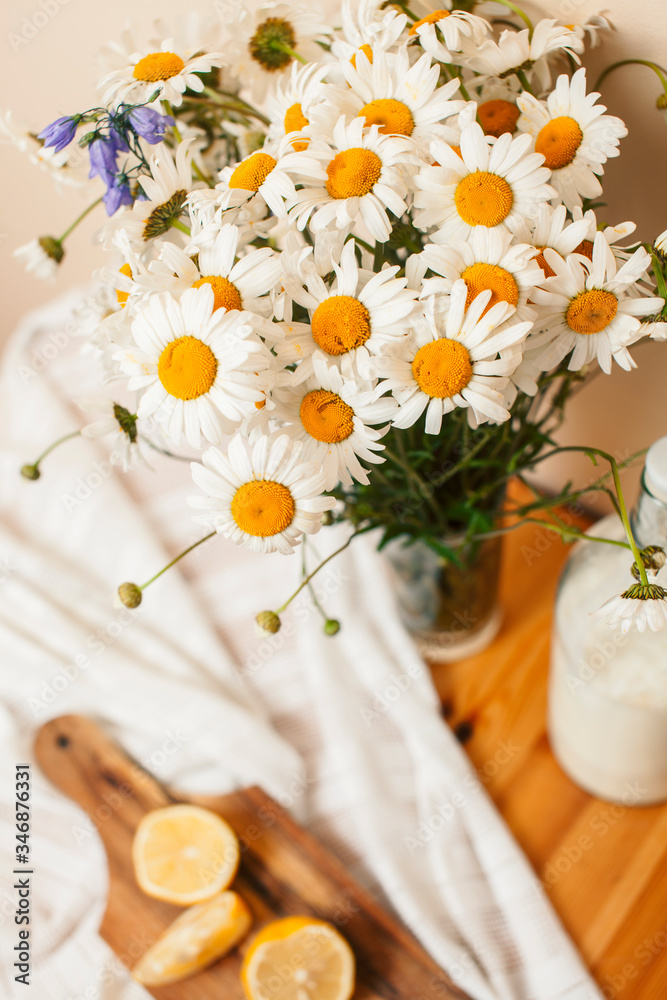 Simply stylish wooden kitchen with bottle of milk and glass on table, summer flowers camomile, healthy foog moring concept Simply stylish wooden kitchen with bottle of milk and glass on table, summer flowers camomile, healthy foog moring concept