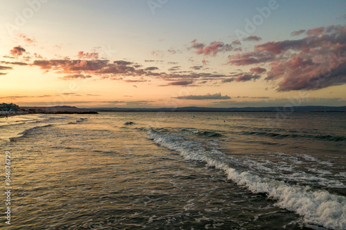 Sea surface with blue water waves under yellow and purple sunset sky.