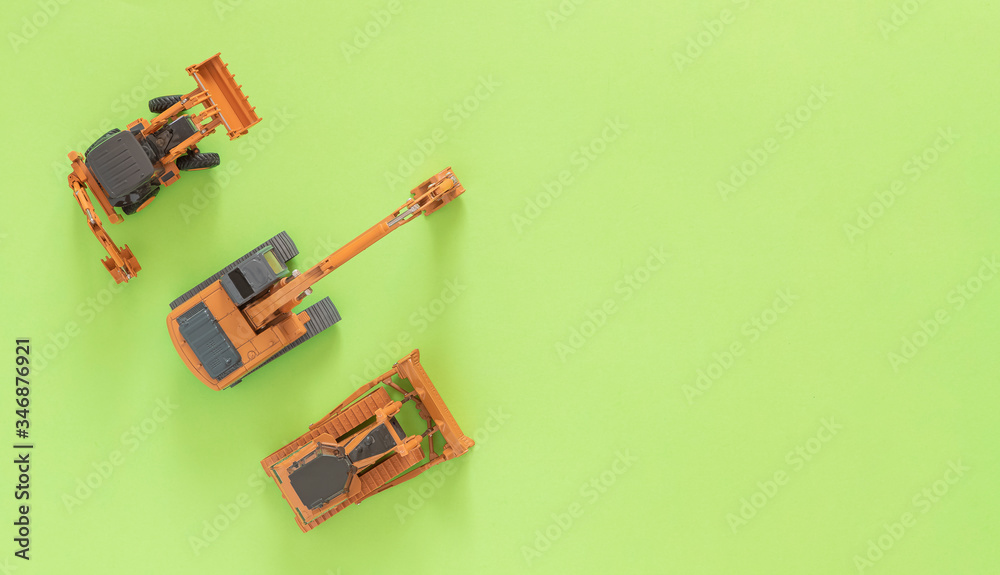 Fototapeta premium Toy models frontal loader, mining excavator and bulldozer. Green background. Top view. Flat lay. A lot of copy space. 