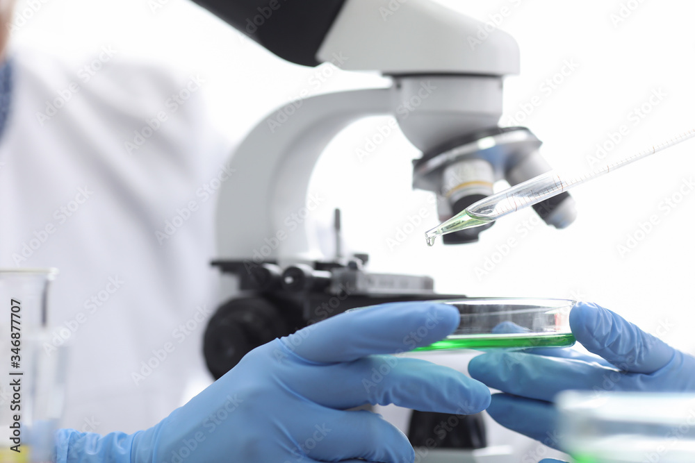 Microscopic examination particles, gloved hands Microscopic examination particles, gloved hands
