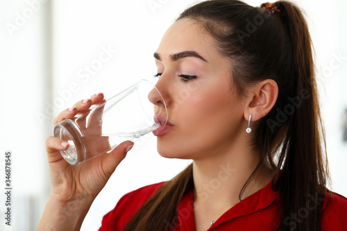 Beautiful girl at work drinks water from glass