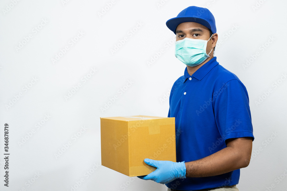 Delivery man blue uniform wearing rubber gloves and mask holding parcel cardboard box on white background. Delivery man blue uniform wearing rubber gloves and mask holding parcel cardboard box on white background.