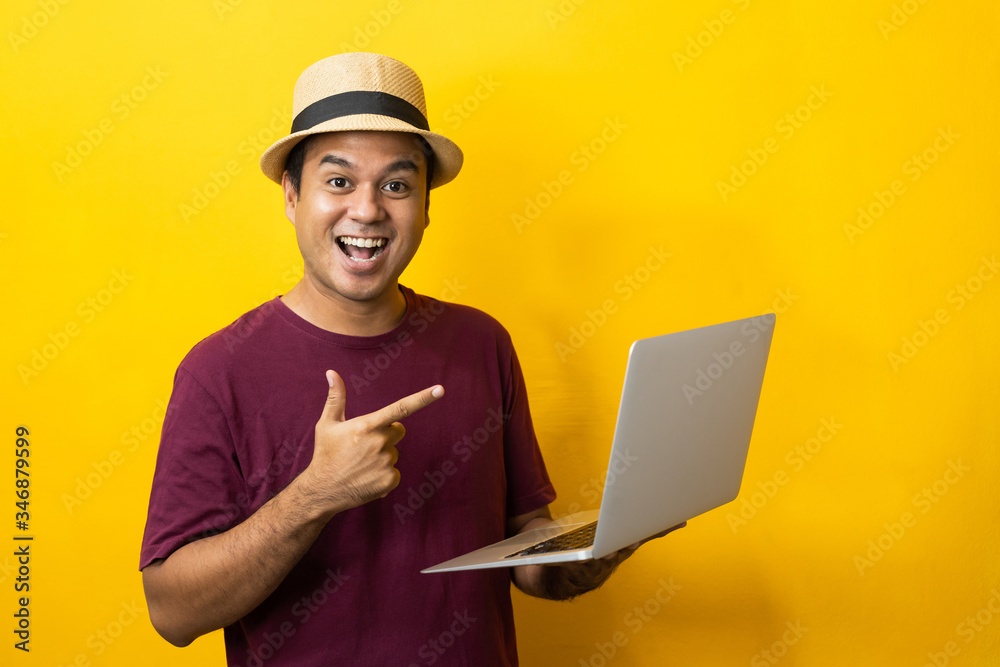 Asian man red shirt with hat using laptop on isolated yellow background. Asian man red shirt with hat using laptop on isolated yellow background.