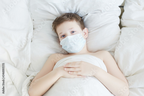 Little boy in Mask. Epidemic concept. Coronavirus. Kid in bed photo