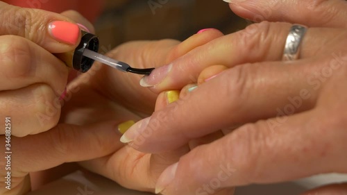 Painting nails with hybrid varnish in a beauty salon. Pink and purple nail polish
