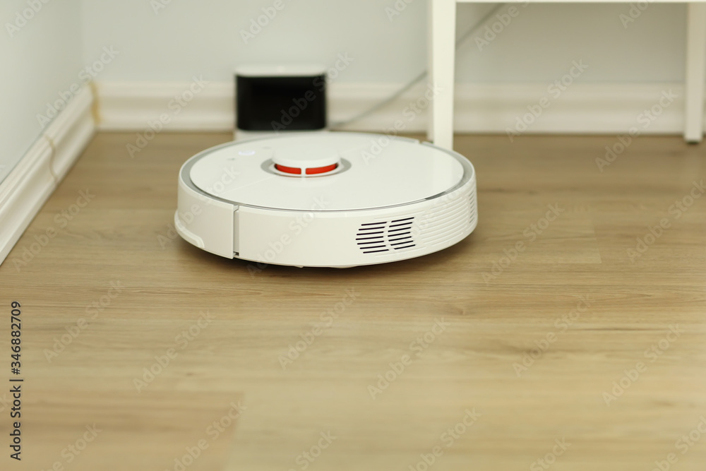 white robotic vacuum cleaner. The robot is controlled by voice commands for direct cleaning. Modern technology of smart cleaning. scheduled cleaning of the apartment. selective focus