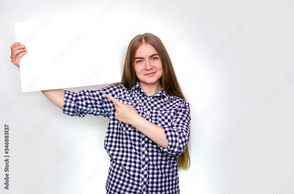 A young girl in a plaid shirt with long hair holds a large sheet, a frame for text in front of her, above herself, from the side. The girl demonstrates, offers, points A young girl in a plaid shirt with long hair holds a large sheet, a frame for text in front of her, above herself, from the side. The girl demonstrates, offers, points