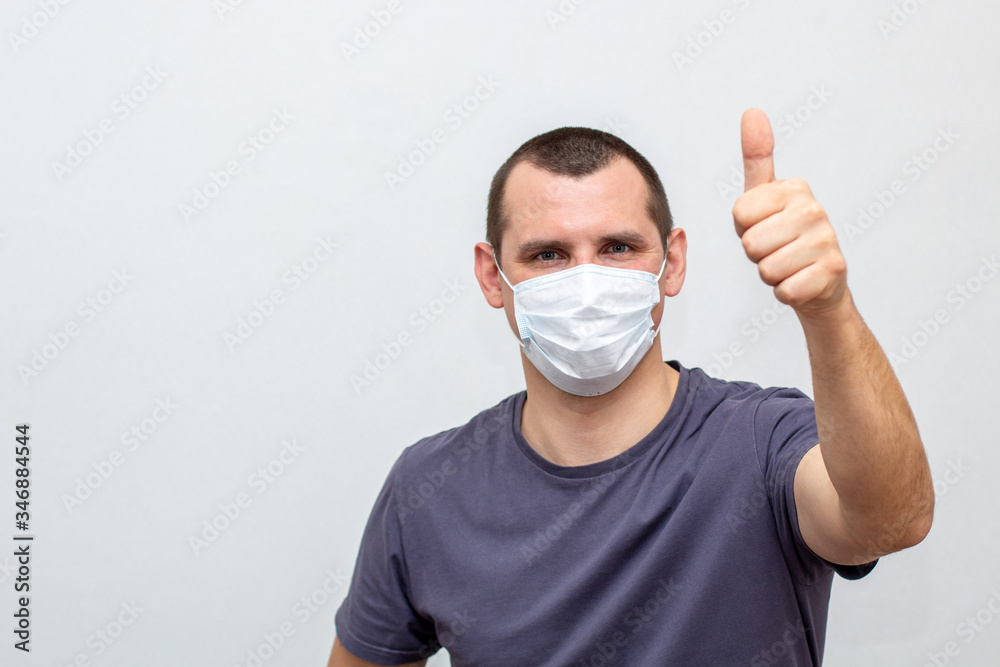 man in medical mask on his face showing thumb up on a white background. man in medical mask on his face showing thumb up on a white background.