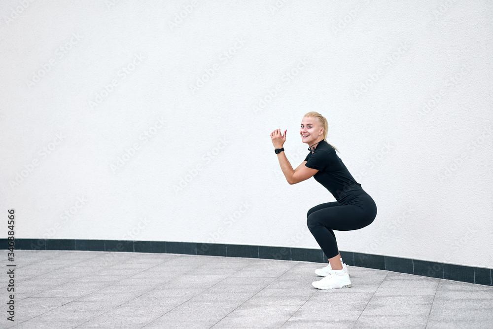 Obraz premium Young attractive sporty girl wearing black sportswear training on white wall background. Concept active and healthy life.