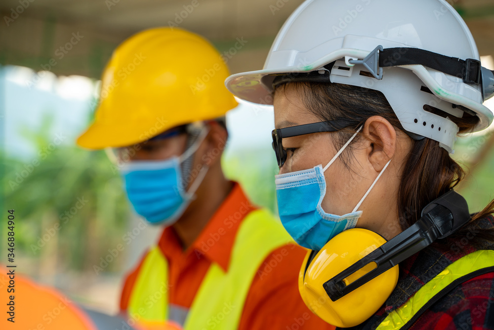 Engineer wearing protective mask to Protect Against Covid-19 working at construction site,Architect Engineer Meeting People Brainstorming Concept.