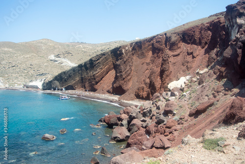 A view of sheer volcanic cliffs on the holiday island of Santorini. Red beach on the south coast. Geological formations from ancient eruptions of the Volcano.