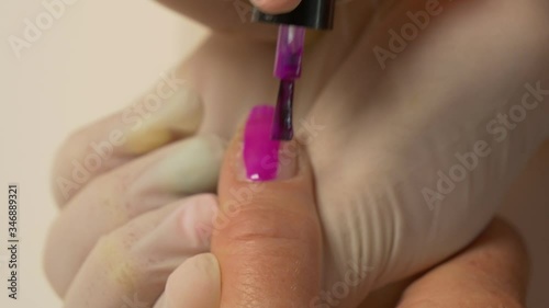 Beautician in protective gloves paints nails