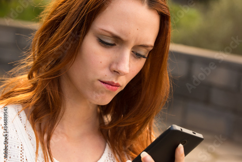 Chica joven y wuapa haciendo un selfie o videoconferencia con el teléfono mobil, algo muy de moda en los millennials que estan muy conectados tecnologicamente. photo