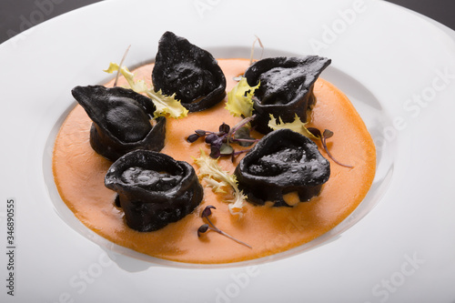 Black ravioli pasta with orange sauce