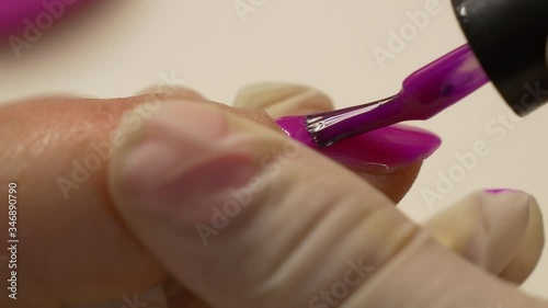 Beautician in protective gloves paints nails