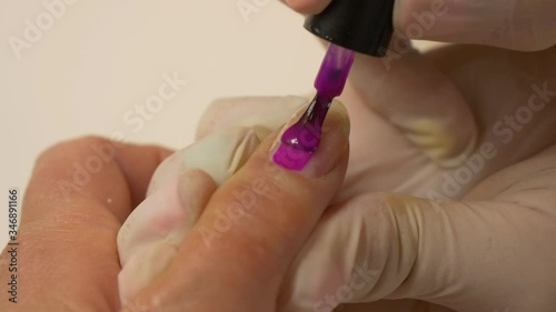 Beautician in protective gloves paints nails