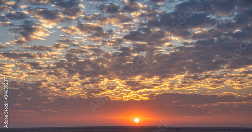 Tableau sur toile Soleil au couché qui transperce un ciel nuageux