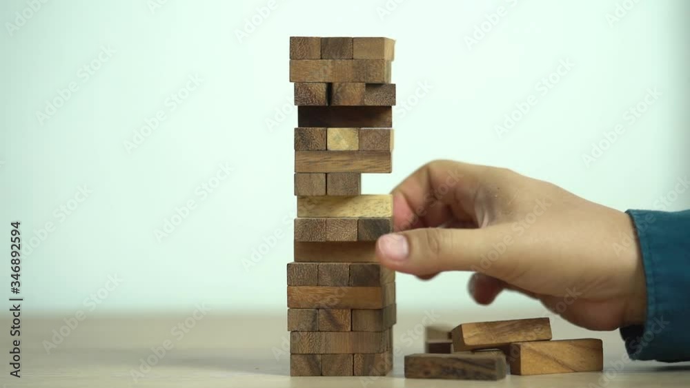 Business risks concept. Hand pulls out wooden brick with jenga game. jenga falls