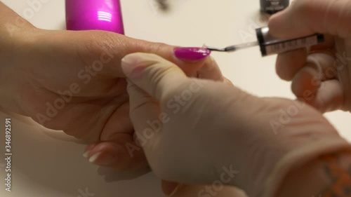 Beautician in protective gloves paints nails
