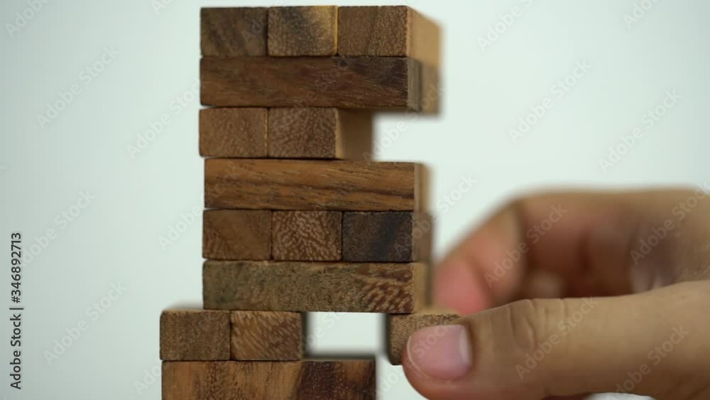 Business risks concept. Hand pulls out wooden brick with jenga game. jenga falls