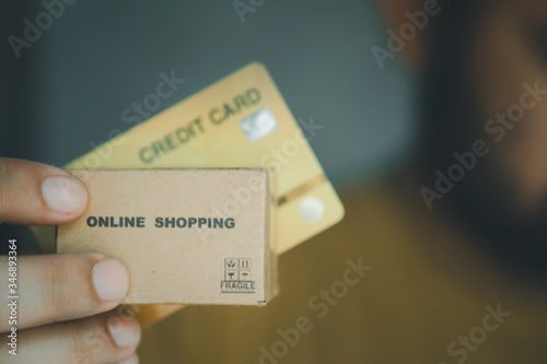 Hands holding credit card and miniature brown cardboard box online shopping.