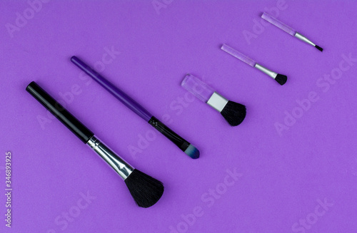 Composition with professional makeup brushes on violet background