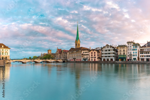 Famous Fraumunster church with its reflection in river Limmat at pink sunrise in Old Town of Zurich, the largest city in Switzerland