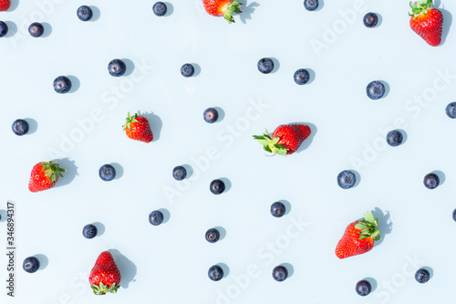 Fruit pattern of blueberries and strawberries. Blue background flatlay
