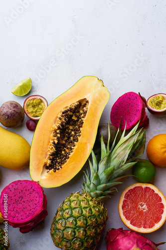 Flat lay tropical exotic fruits with copy space. Vegetarian dessert. Healthy summer food ingredients: papaya, pitaya, pineapple, orange, lime, grapes and mango.