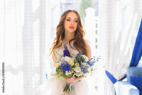 Pretty young bride posing with bouquets of flowers