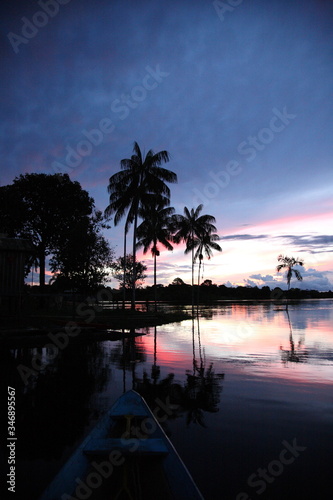 Landscape of Amazon jungle river with sailing boat and coconut palm tree during sunset in Brazil