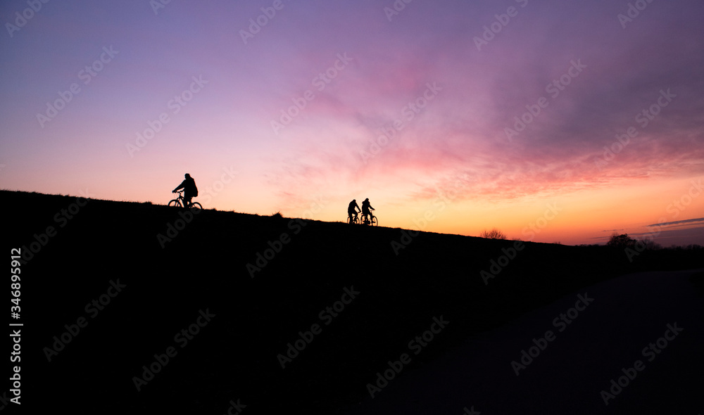 People cycling on the Sava river embankment during beautiful, colorful sunset at evening People cycling on the Sava river embankment during beautiful, colorful sunset at evening