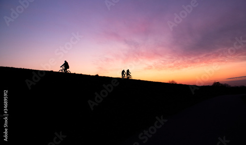 People cycling on the Sava river embankment during beautiful, colorful sunset at evening
