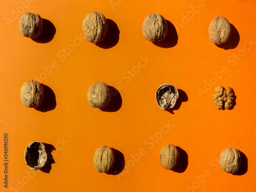 whole and cracked walnuts pattern on orange background, horizontal