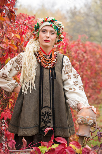 Beautiful girl in national dress. With an ancient clay pot. Antique clothing of the late 19th century. Beautiful dress and skirt on a woman. Beautiful autumn and leaves. Clothing of the late 19th