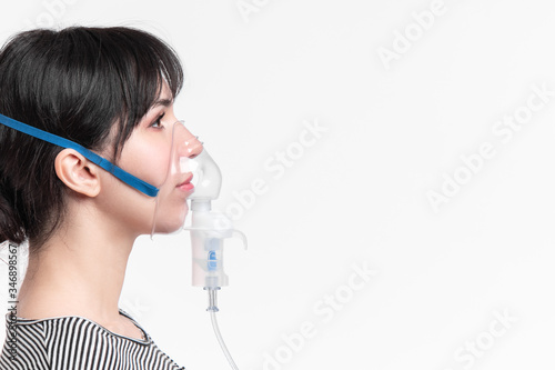 profile picture of brunette woman with inhalation mask on her face. patient inhale medicine