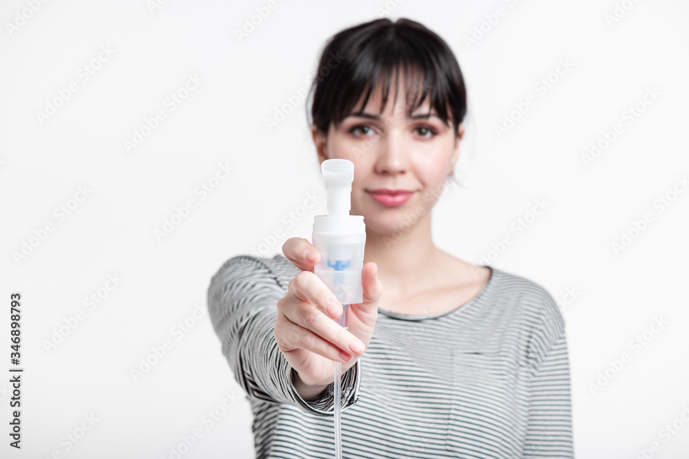 smiling brunette woman holding inhaer in front of her face. pulmonary diseases recovery and seasonal allergy treatment concept smiling brunette woman holding inhaer in front of her face. pulmonary diseases recovery and seasonal allergy treatment concept