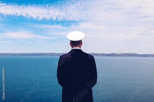 Obraz na płótnie Strong posture of a captain looking at the sea and faraway land on the horizon
