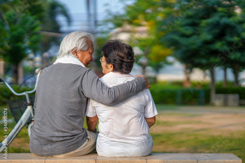 
A senior couple is happily riding their bicycles in the park in the morning.