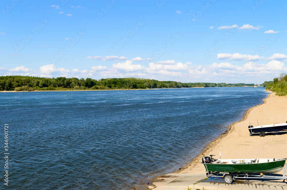 Amazing rippling blue river with sandy shore, green trees and boats