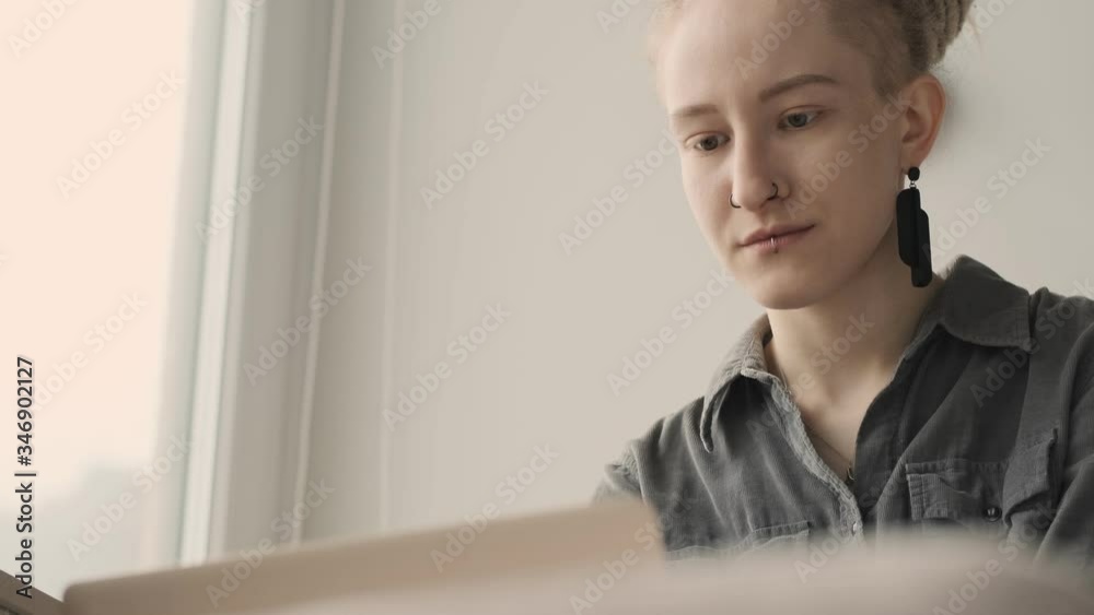 Concentrated girl with dreadlocks indoors using laptop computer near window Concentrated girl with dreadlocks indoors using laptop computer near window