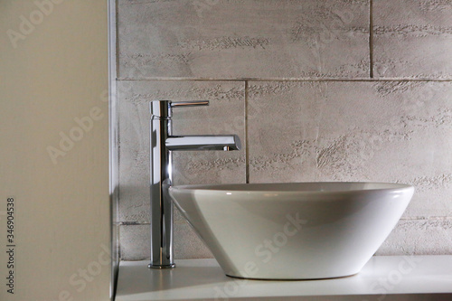 Dettaglio di rubinetto moderno su lavabo elegante dentro un bagno.