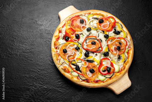 VEGETARIAN pizza on a black background, tomato-based with mozzarella, olives, tomatoes, eggplant, sweet pepper, zucchini, onion and mushrooms