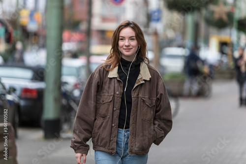 Young Caucasian Woman Smiling on Sidewalk Listening to Earphones © Nektarstock